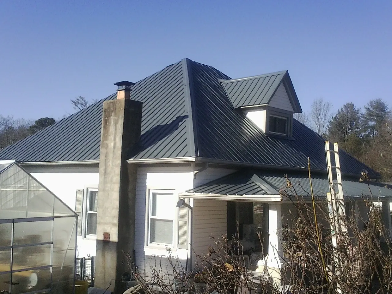 Dark blue standing seam metal roof on a white farmhouse with dormer — Slate & Tile Roof Repair by Roofing Brothers in Limestone