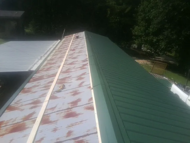 Old rusted panels beside newly installed green metal roofing — Wind Damage Roof Repair by Roofing Brothers in Limestone