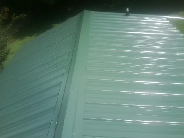 New green metal panels meeting at the ridge of a roof — Flat Roof Repair work by our crew in Limestone
