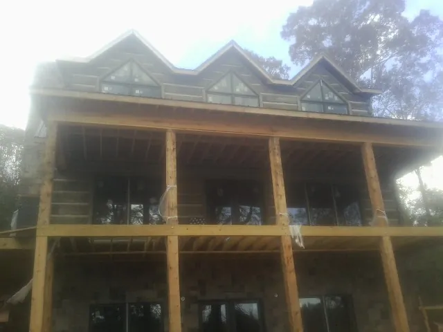 Dormers and porch framing on a large log home under construction — Roof Coating work by our crew in Limestone
