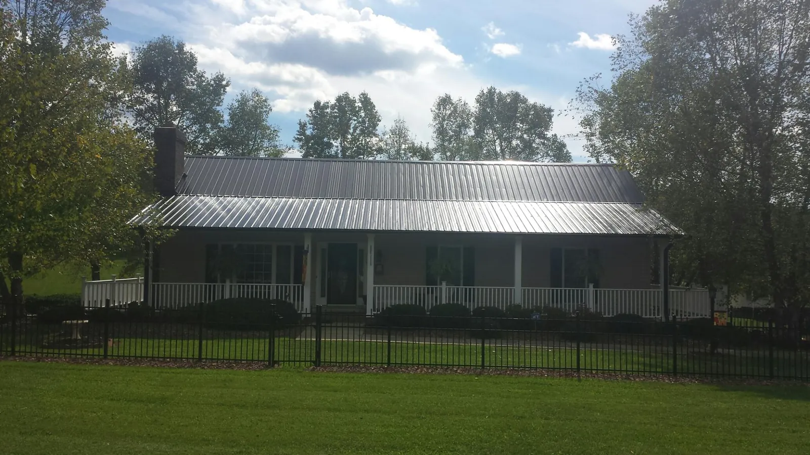 Gray metal roof on a brick ranch with a full width front porch — Gutter Guard Installation work by our crew in Limestone