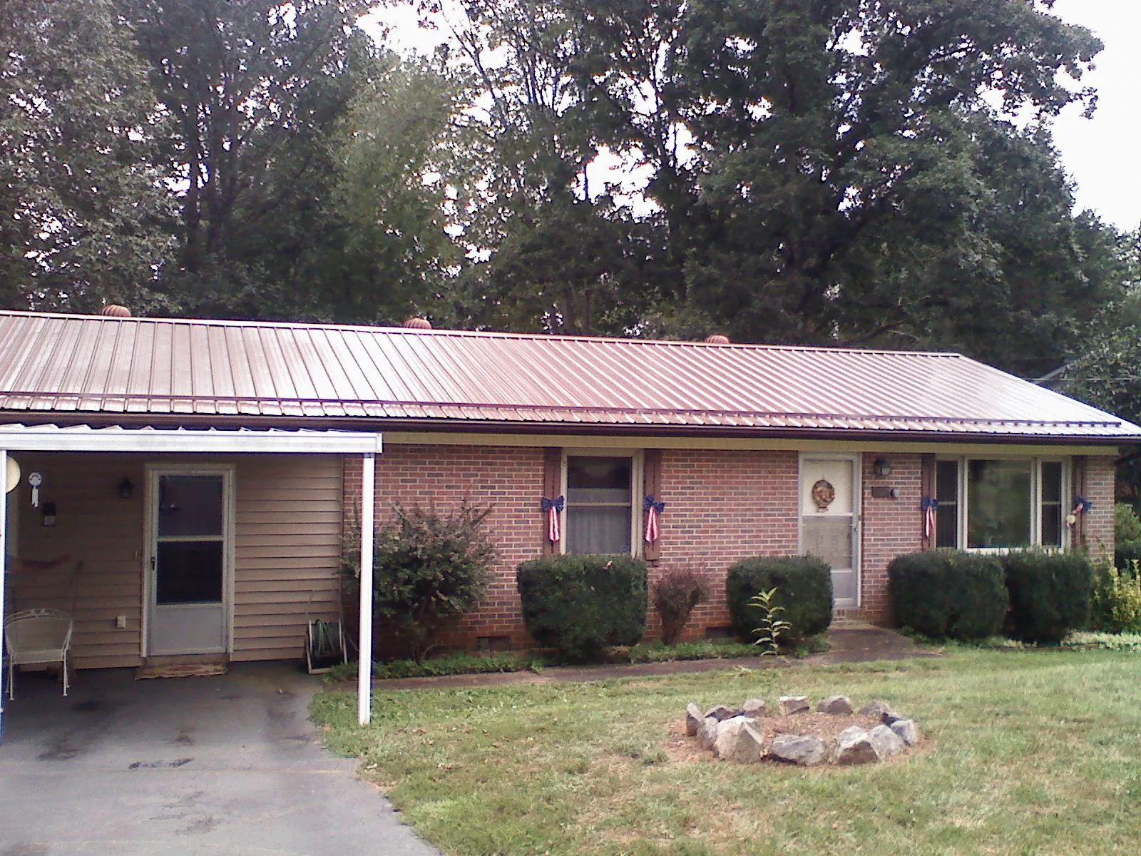 Bronze metal roof and carport on a brick ranch home — Roof Repair work by our crew in Limestone