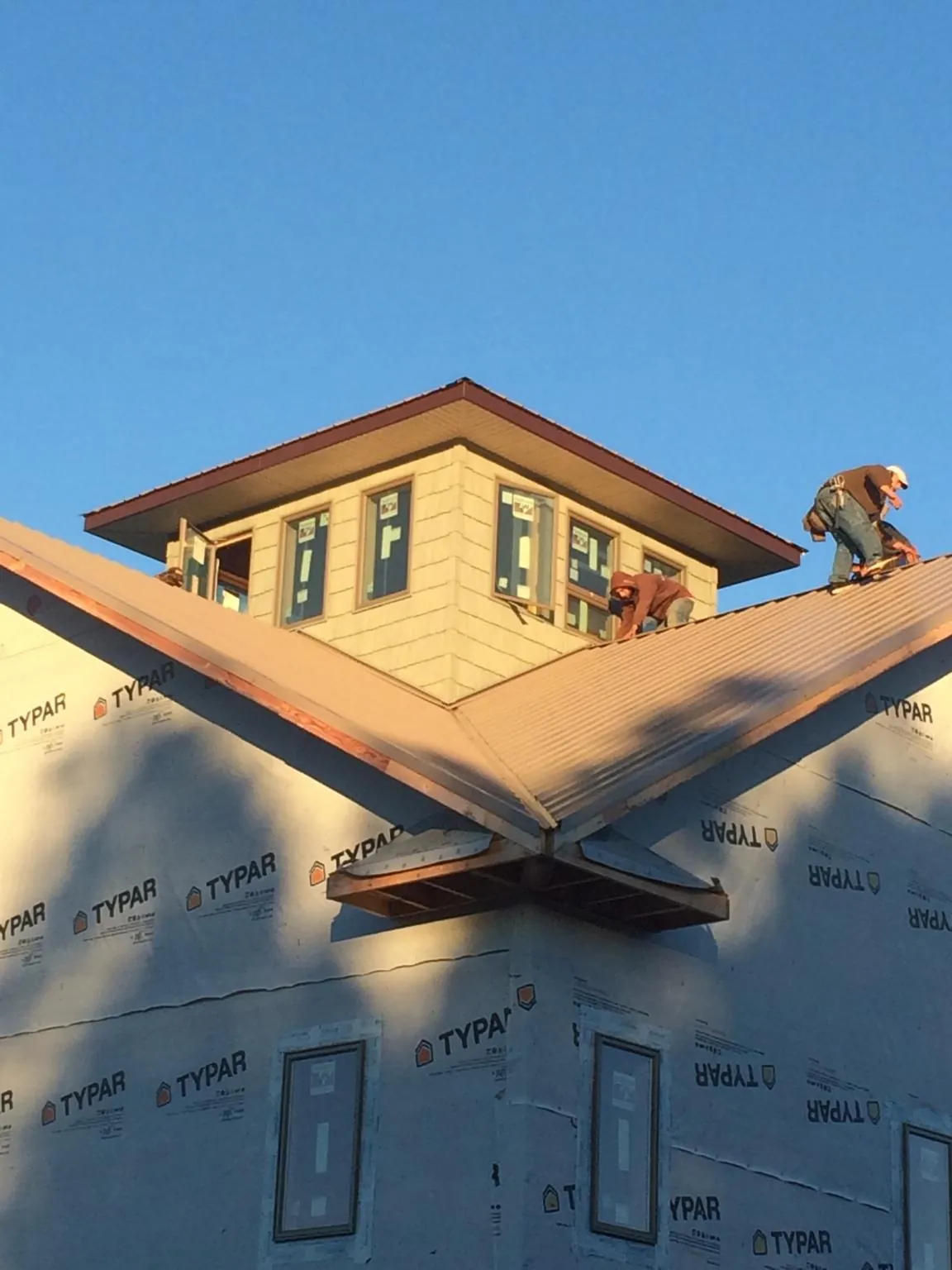 Roofers working around a rooftop cupola on a new metal roof at sunset — Roof Waterproofing in Limestone by Roofing Brothers